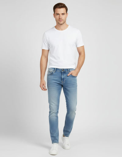 Man wearing a white t-shirt and light blue jeans on a plain background