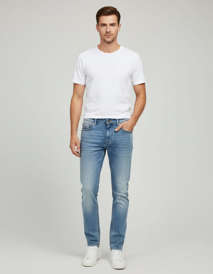 Man wearing a white t-shirt and light blue jeans on a gray background