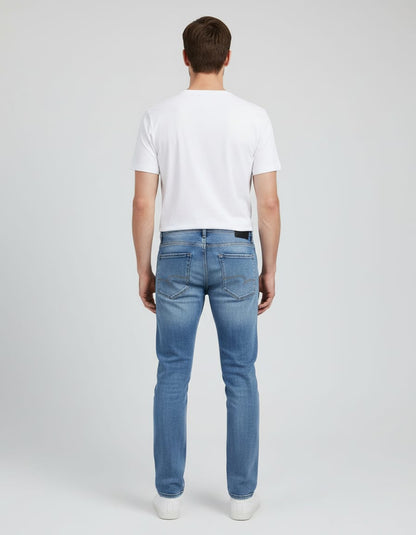Man wearing a white t-shirt and blue jeans on a light gray background