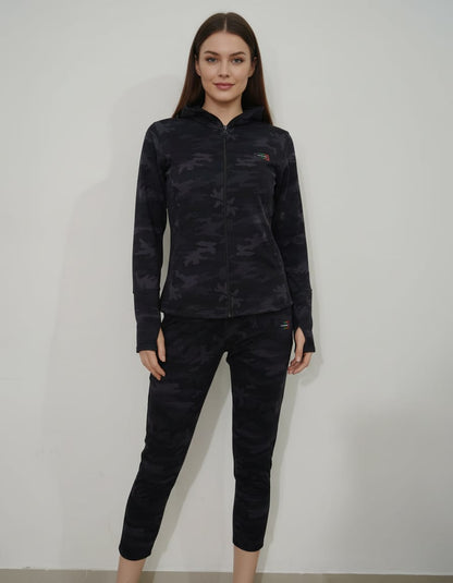 Woman wearing a black camouflage long-sleeve top and pants against a white background