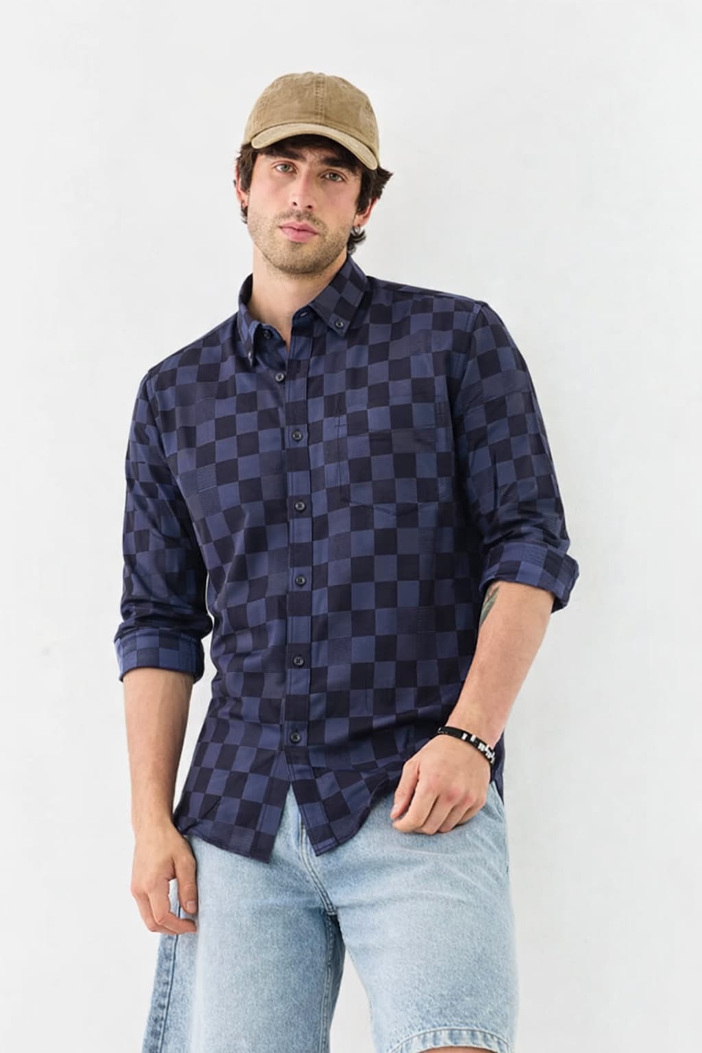 Man wearing a checkered shirt and cap against a white background