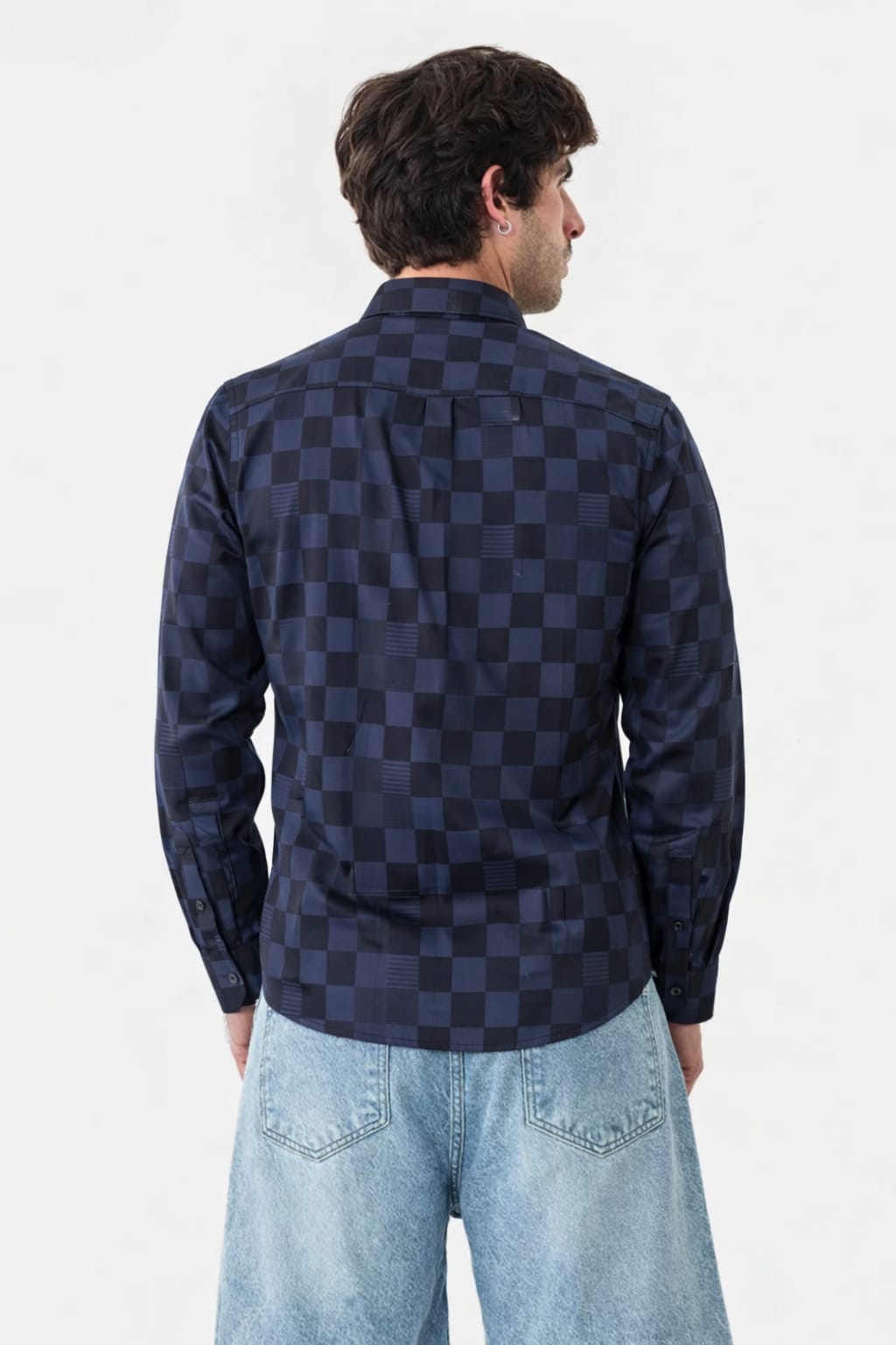 Person wearing a navy and black checkered shirt with light blue jeans on a white background