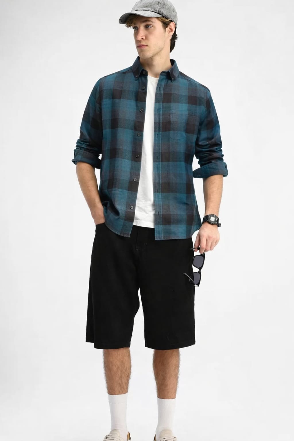 Man wearing a blue plaid shirt, white t-shirt, black shorts, and a cap on a white background
