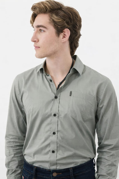 Man wearing a light gray button-up shirt with a small logo on a white background
