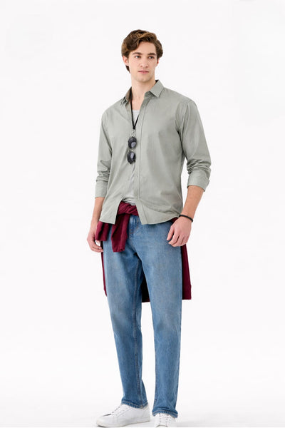 Man wearing a light gray shirt, blue jeans, and white sneakers on a white background