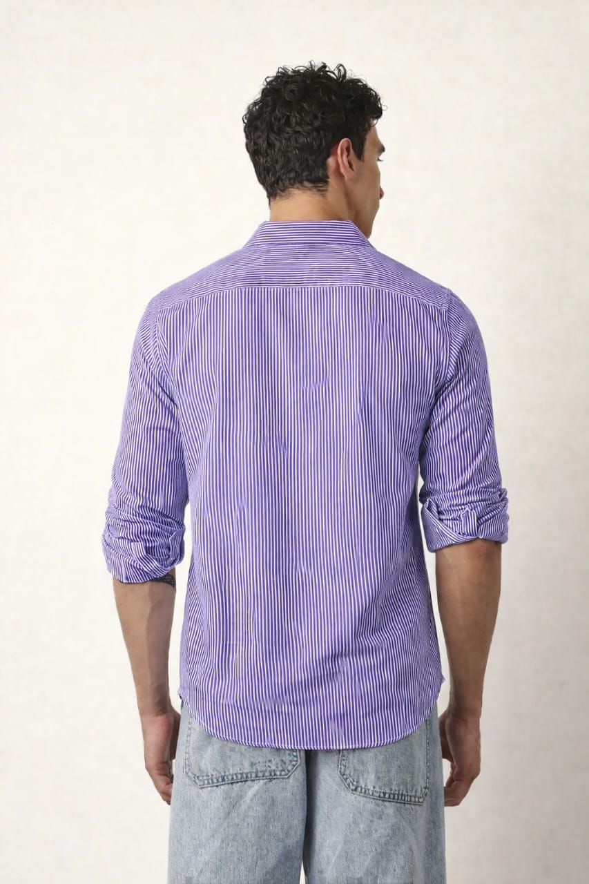 Man wearing a purple striped shirt and light blue jeans against a white background