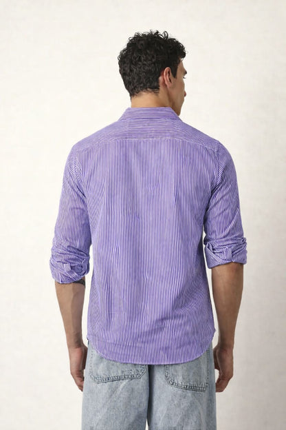 Man wearing a purple striped shirt and light blue jeans against a white background
