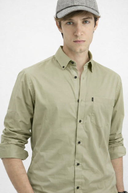 Man wearing a light green button-up shirt and gray cap on a white background