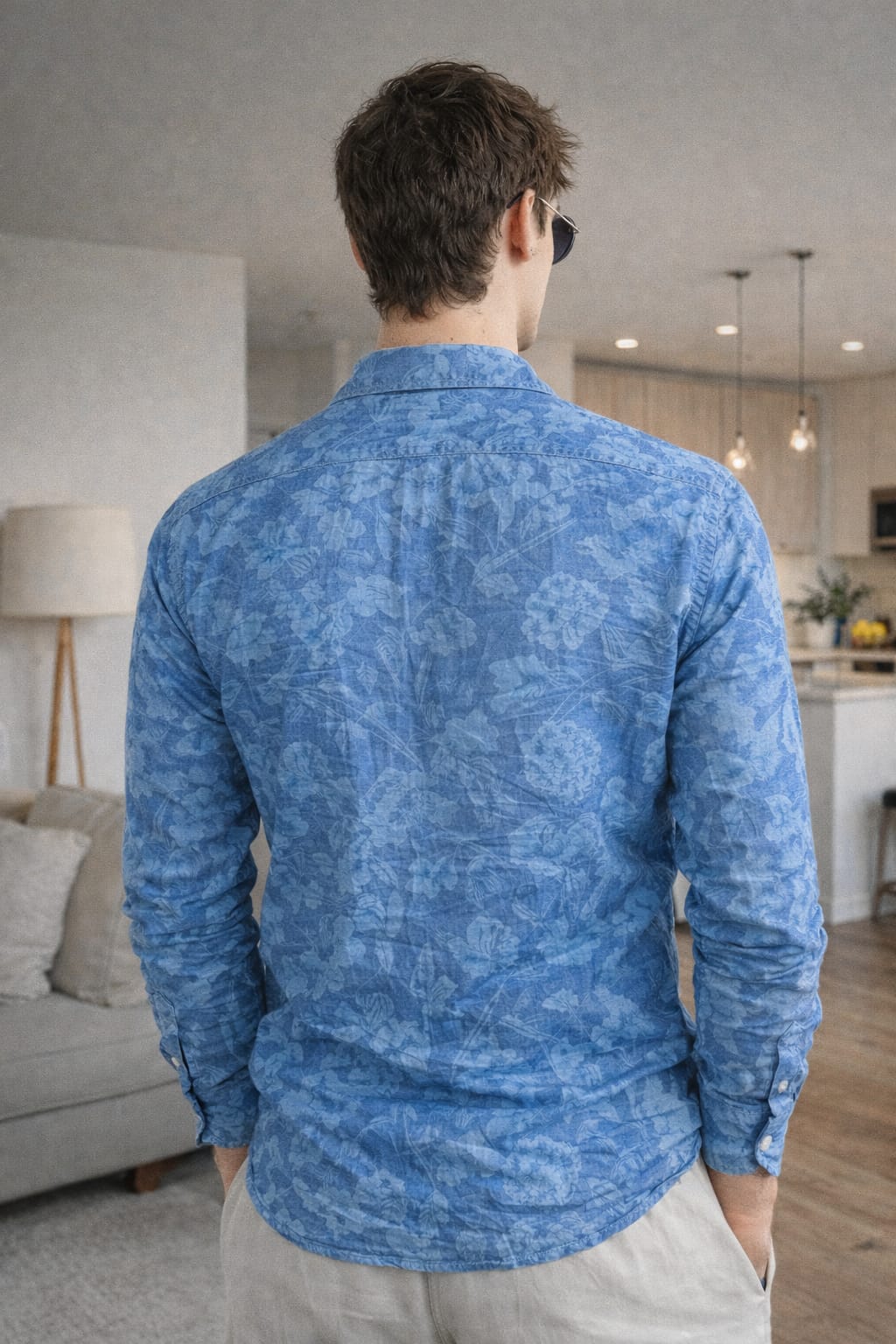 Man wearing a blue patterned shirt in a living room setting