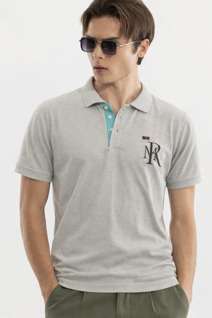 Man wearing a gray polo shirt with a logo on a white background