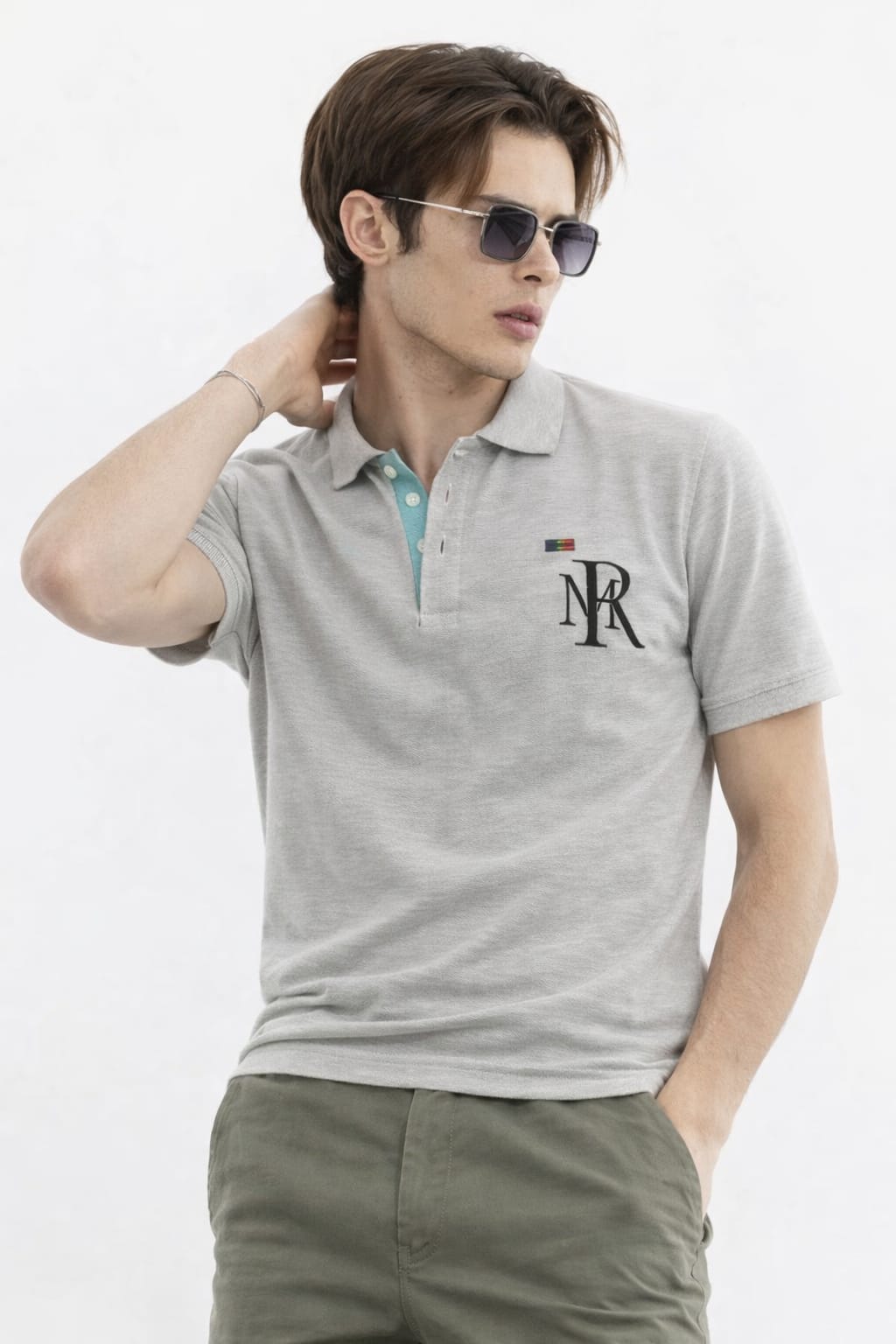 Man wearing a gray polo shirt with a logo on a white background