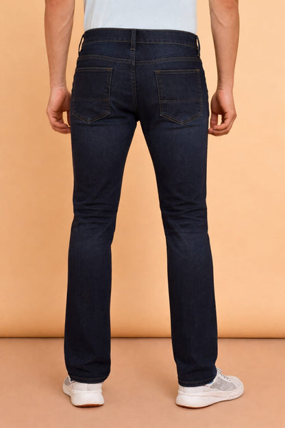 Person wearing dark blue jeans on a beige background
