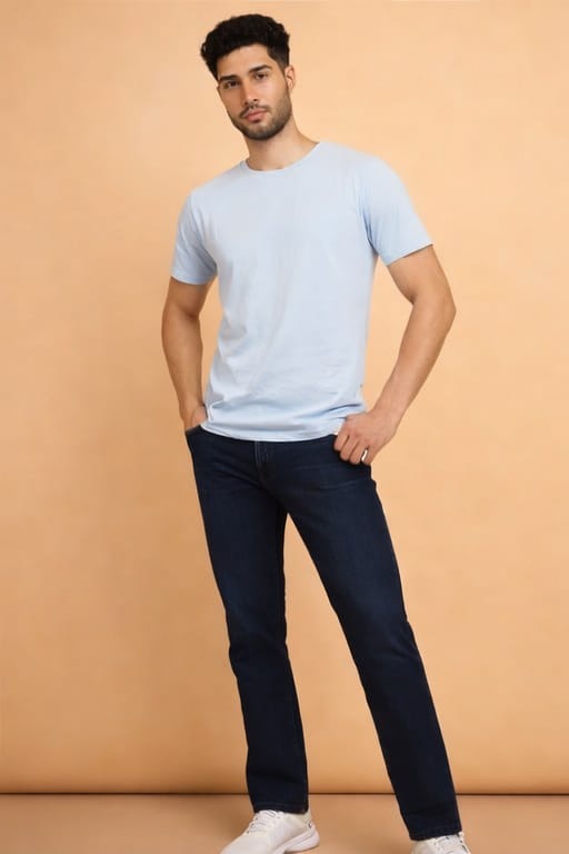 Man wearing a light blue t-shirt and dark jeans against a beige background