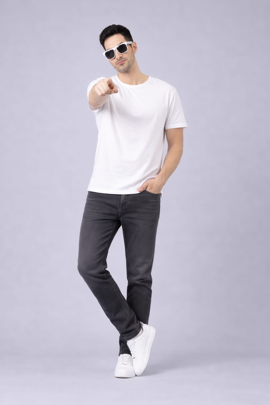 Man wearing a white t-shirt, dark jeans, and sunglasses on a gray background