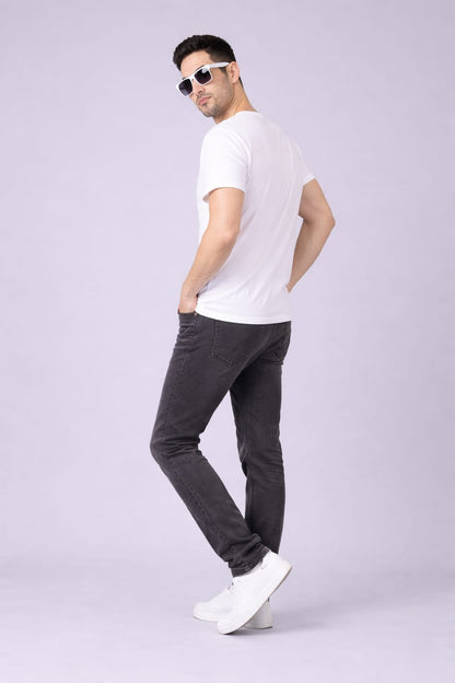 Man wearing a white t-shirt, dark gray pants, and white sneakers on a light gray background