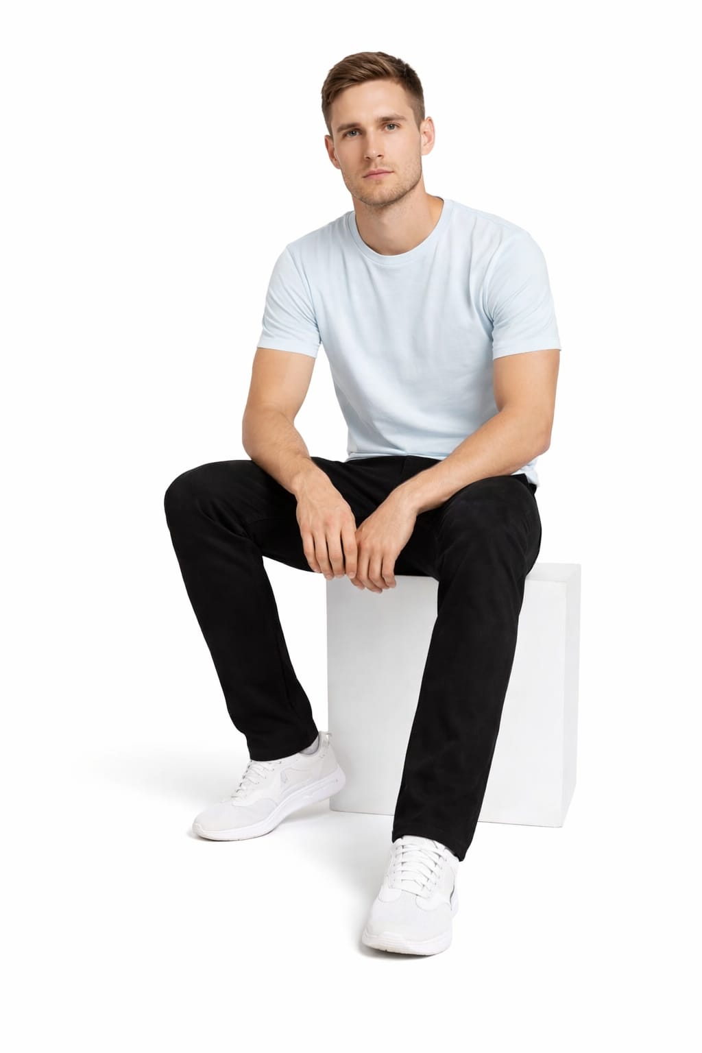 Man sitting on a white cube wearing a white t-shirt and black pants.