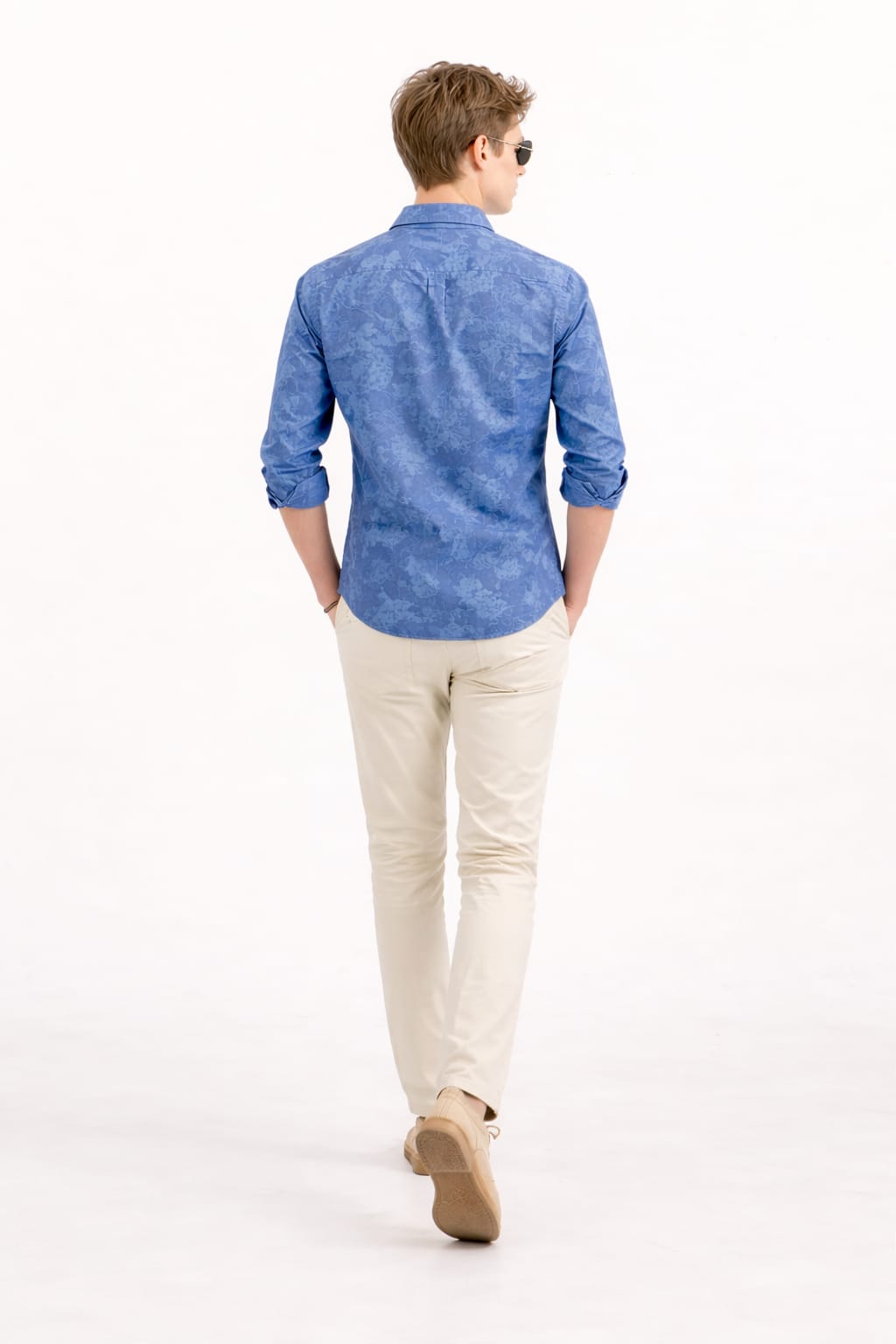 Man wearing a blue shirt and beige pants on a white background
