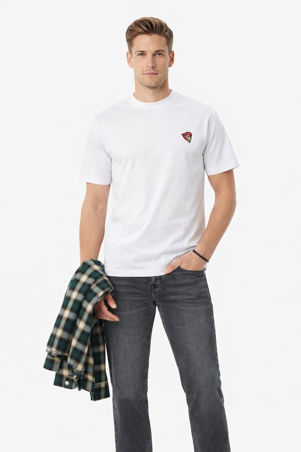 Man wearing a white t-shirt with a red logo and gray jeans, holding a plaid shirt.