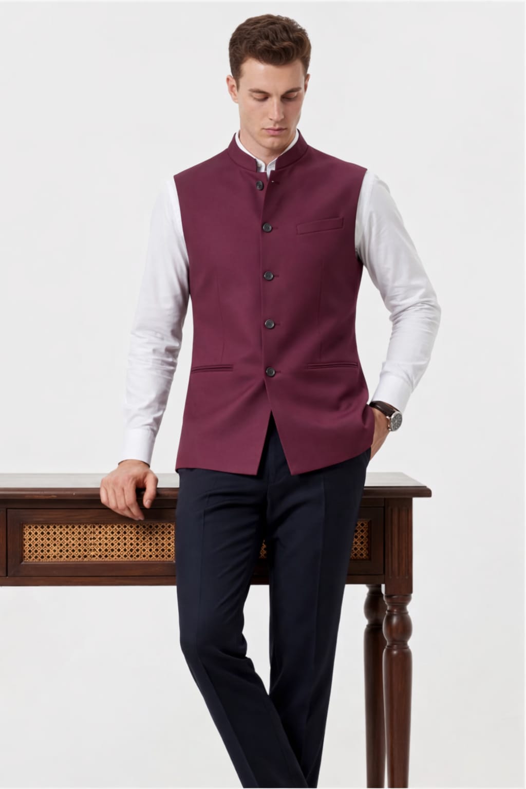Man wearing a maroon vest over a white shirt with dark pants on a white background