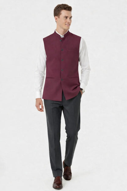 Man wearing a burgundy vest over a white shirt with gray pants on a white background