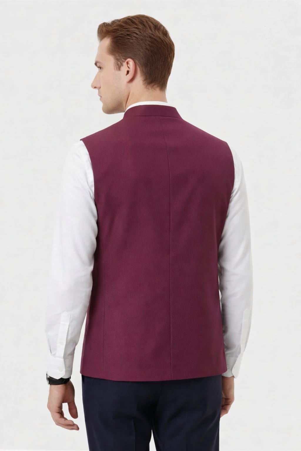 Man wearing a maroon vest over a white shirt on a light gray background