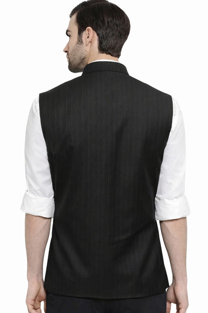Man wearing a black vest over a white shirt on a white background