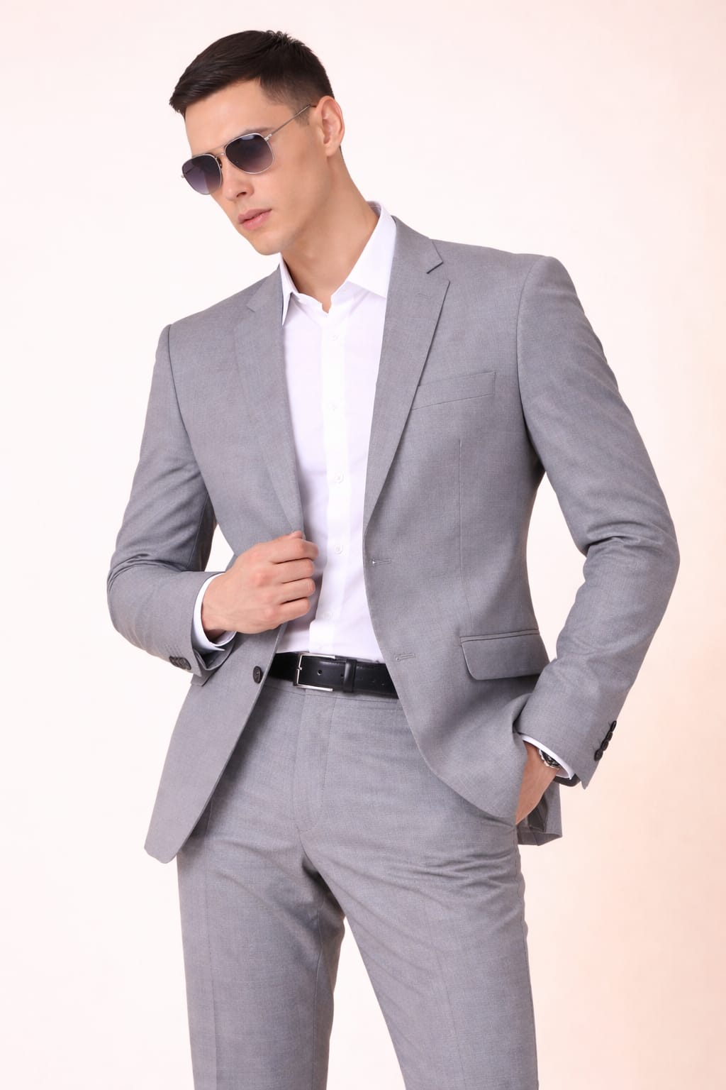 Man wearing a gray suit and sunglasses against a plain background