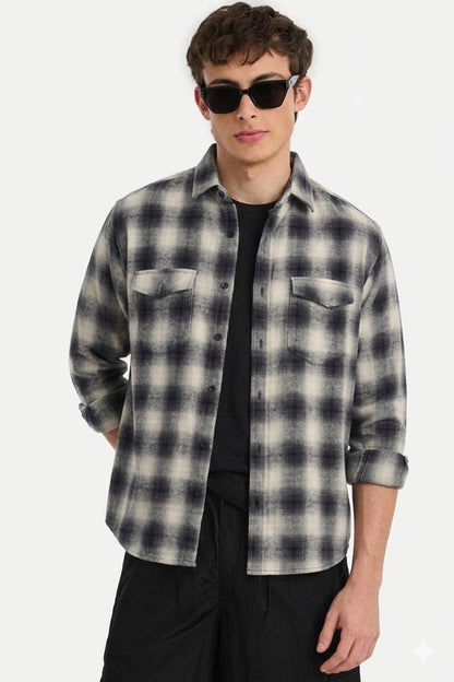 Man wearing a plaid shirt over a black t-shirt with sunglasses on a white background