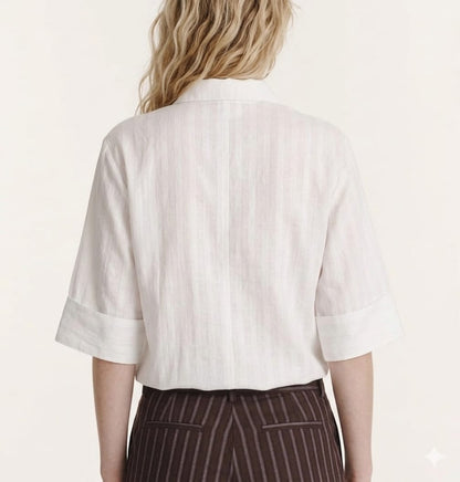 Person wearing a white short-sleeve shirt and brown striped pants on a plain background