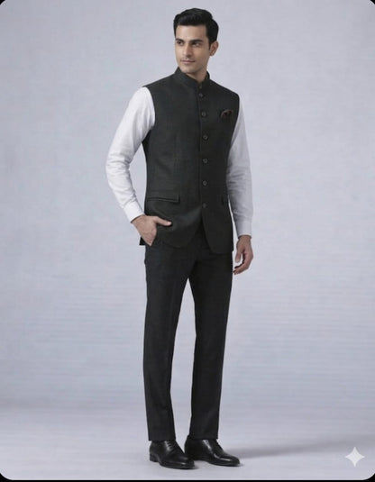 Man wearing a dark gray vest over a white shirt with black pants on a light gray background
