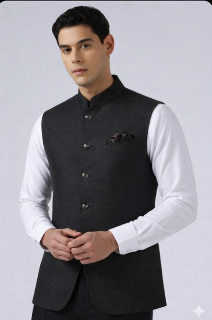 Man wearing a black vest over a white shirt on a gray background