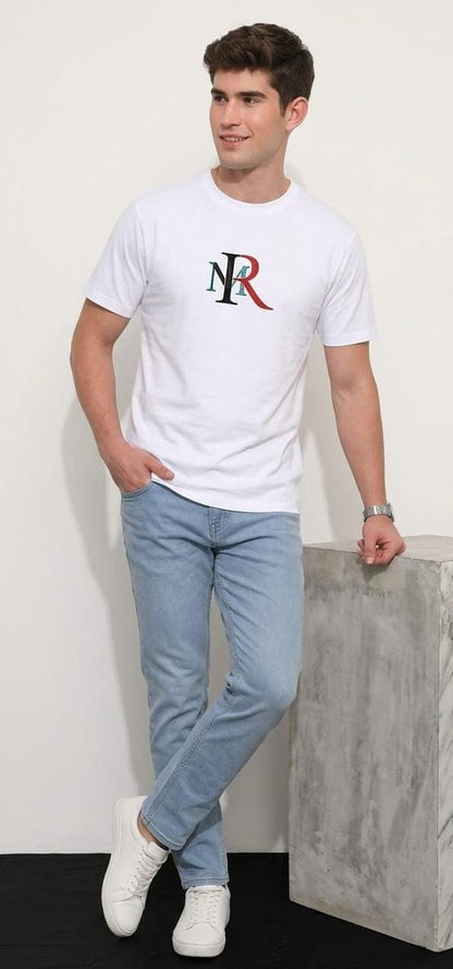 Man wearing a white t-shirt with a logo and light blue jeans against a plain background