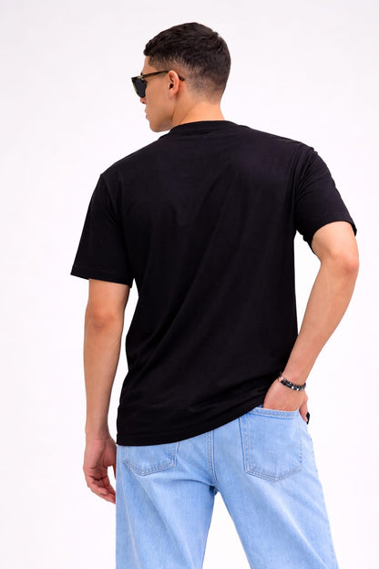 Man wearing a black t-shirt and light blue jeans on a white background