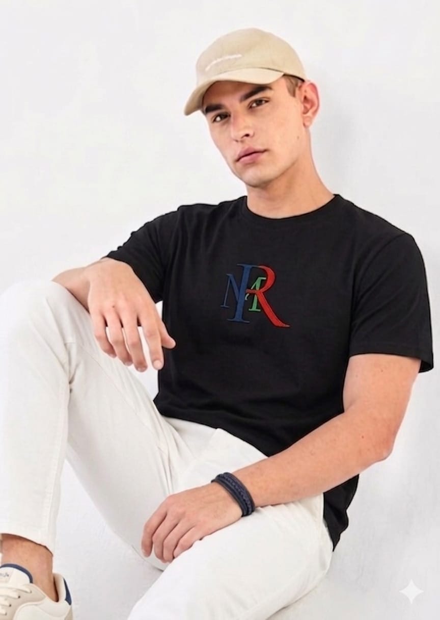 Person wearing a black t-shirt with a logo, sitting against a white background