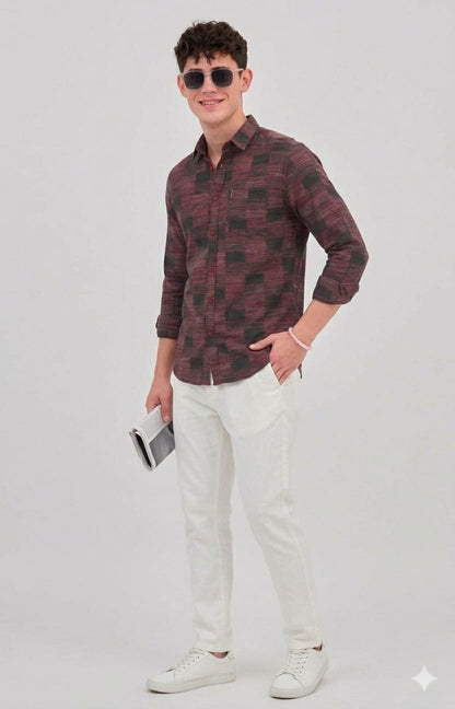 Man wearing a patterned shirt and white pants on a plain background