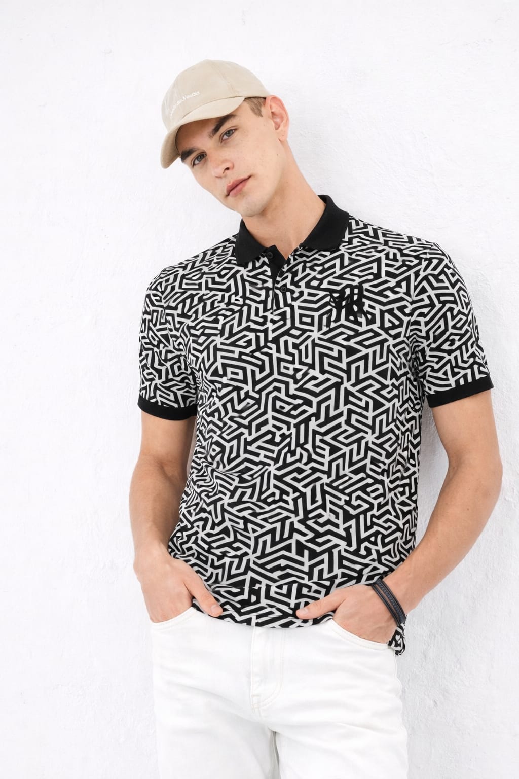 Man wearing a black and white patterned shirt with a cap on a white background