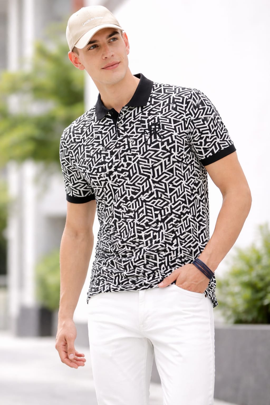 Man wearing a black and white patterned polo shirt with a cap outdoors.