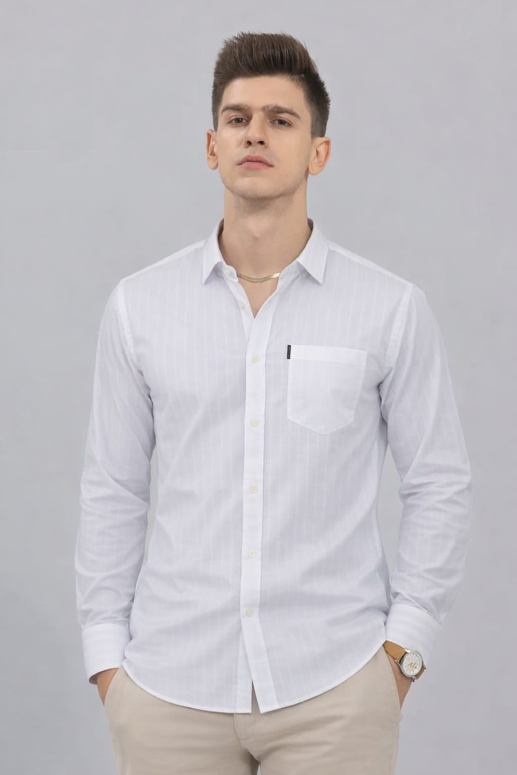 Man wearing a patterned polo shirt with a logo, sitting on a wooden stool against a plain background