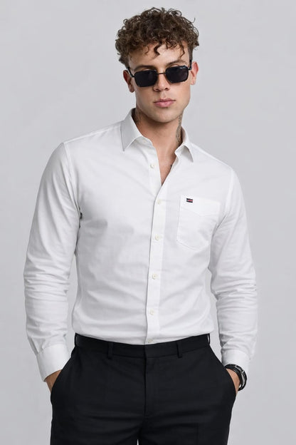Man wearing a white dress shirt and black pants against a gray background