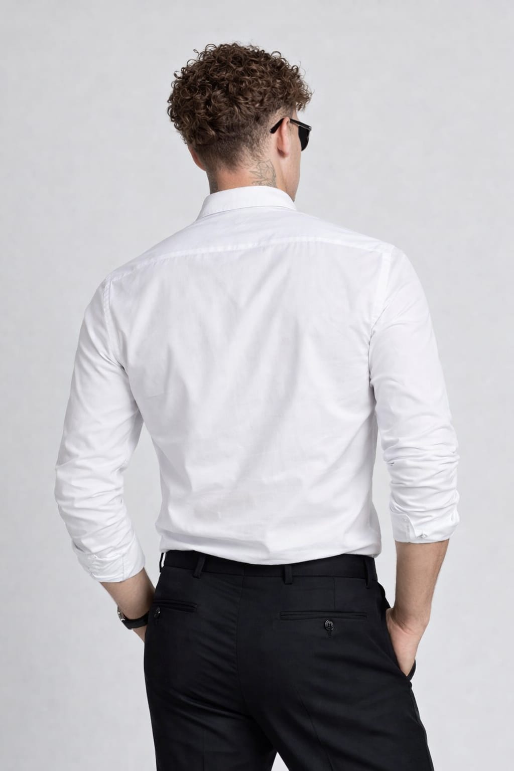 Man wearing a white dress shirt and black pants on a plain background