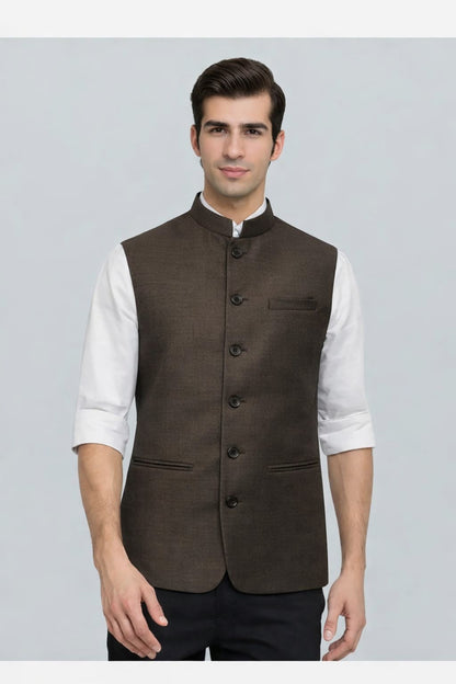 Man wearing a brown vest over a white shirt on a gray background