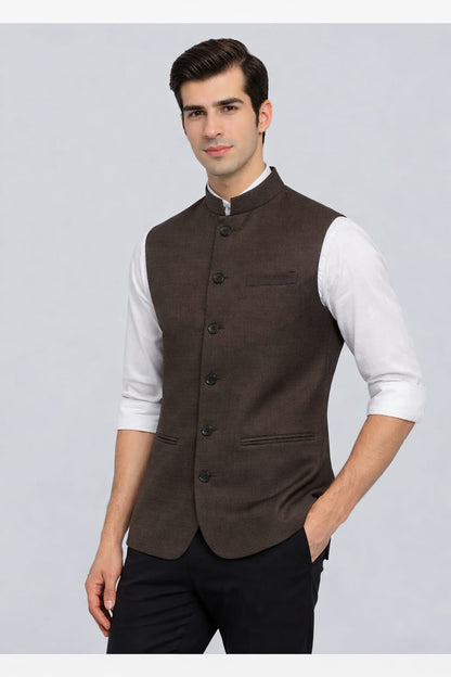 Man wearing a brown vest over a white shirt on a gray background