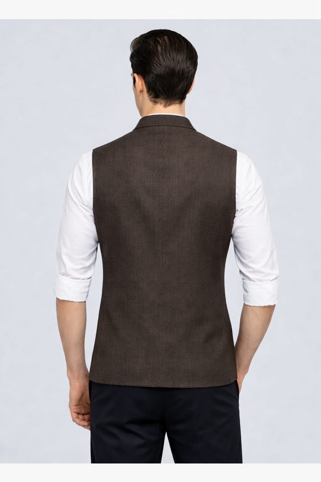 Man wearing a brown vest over a white shirt on a light gray background