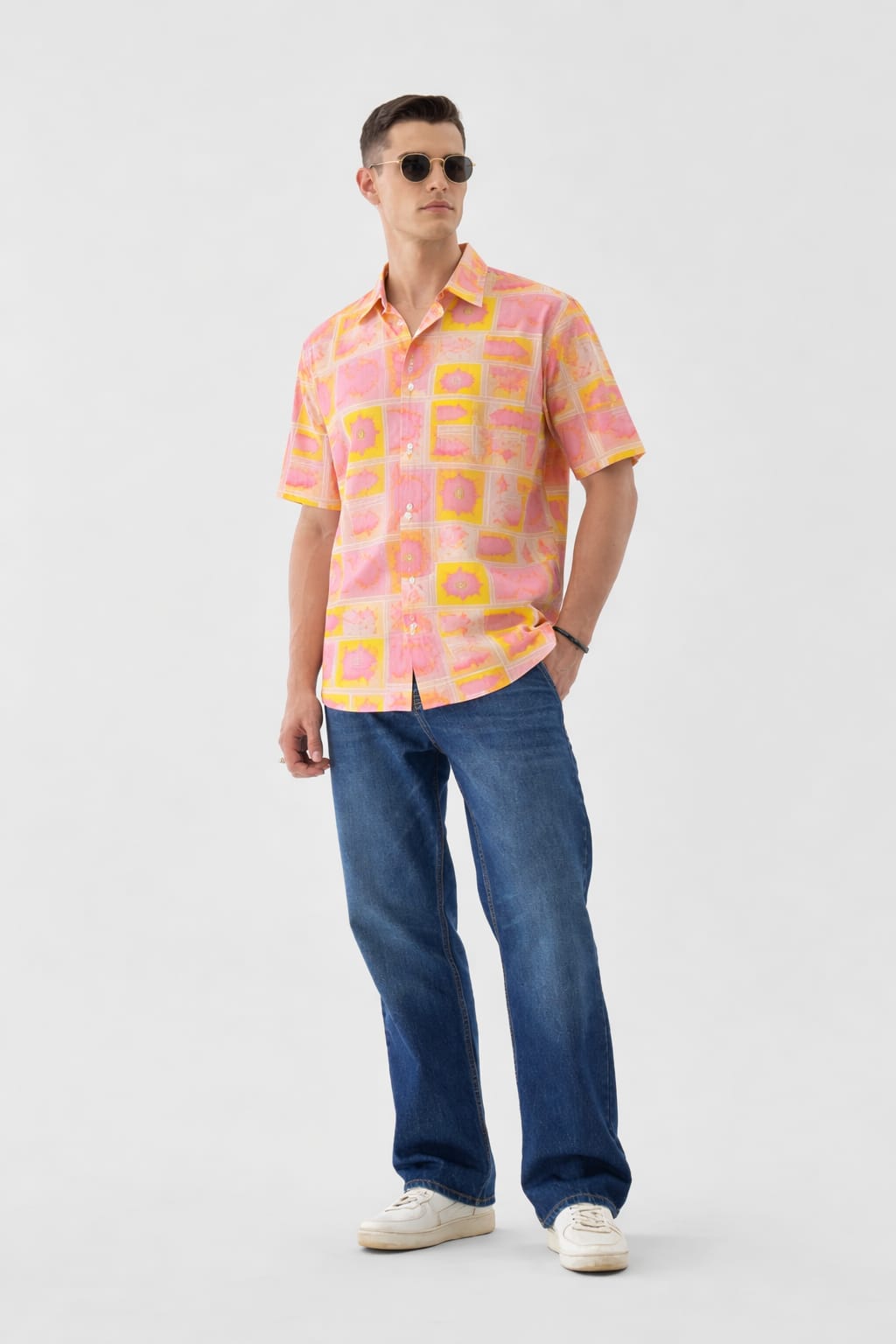 Man wearing a colorful patterned shirt and blue jeans on a white background