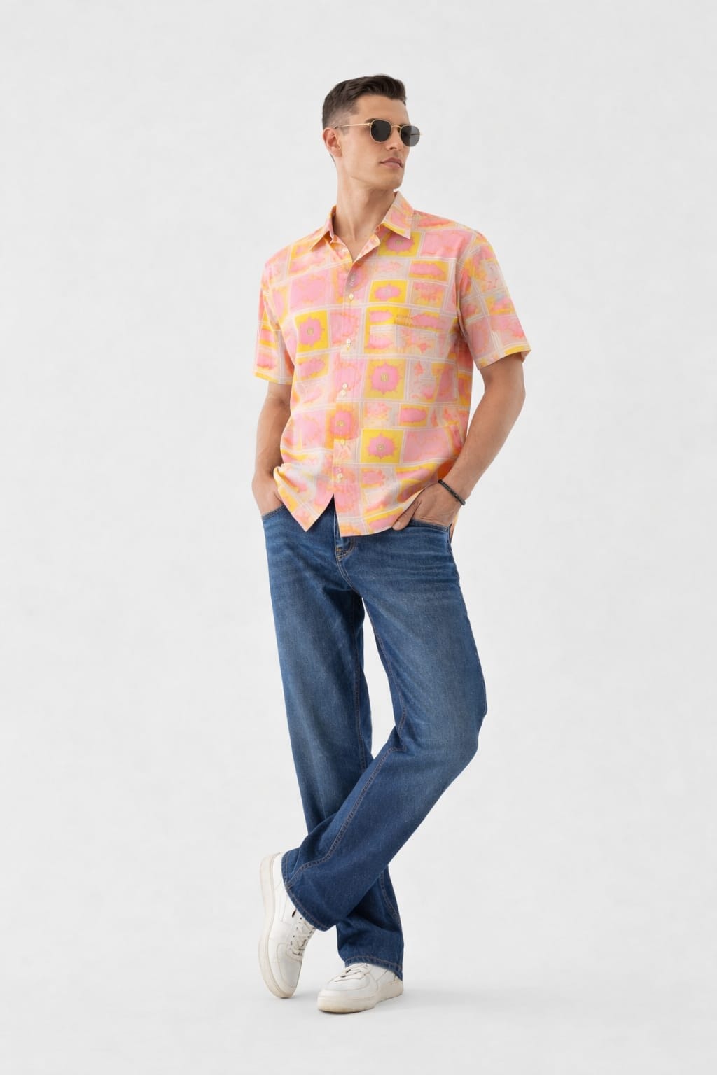 Man wearing a patterned shirt and blue jeans on a white background