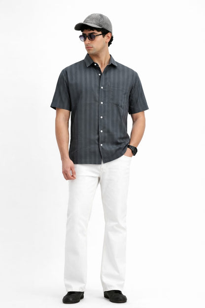 Man wearing a dark gray striped shirt, white pants, and a cap on a white background