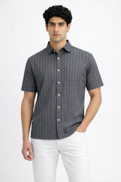 Man wearing a gray striped shirt and white pants on a white background