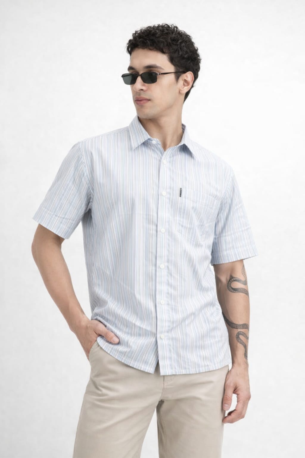Man wearing a light blue striped shirt and beige pants on a white background