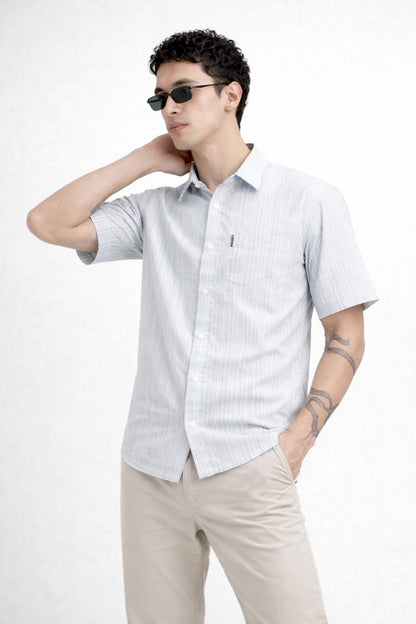 Man wearing a light gray short-sleeve shirt and beige pants on a white background