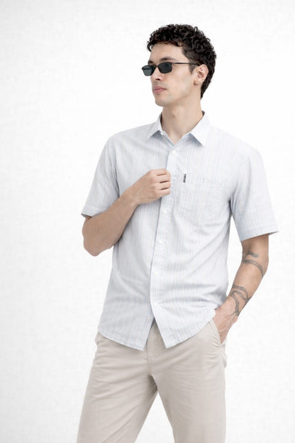 Man wearing a light gray short-sleeve shirt and beige pants on a white background